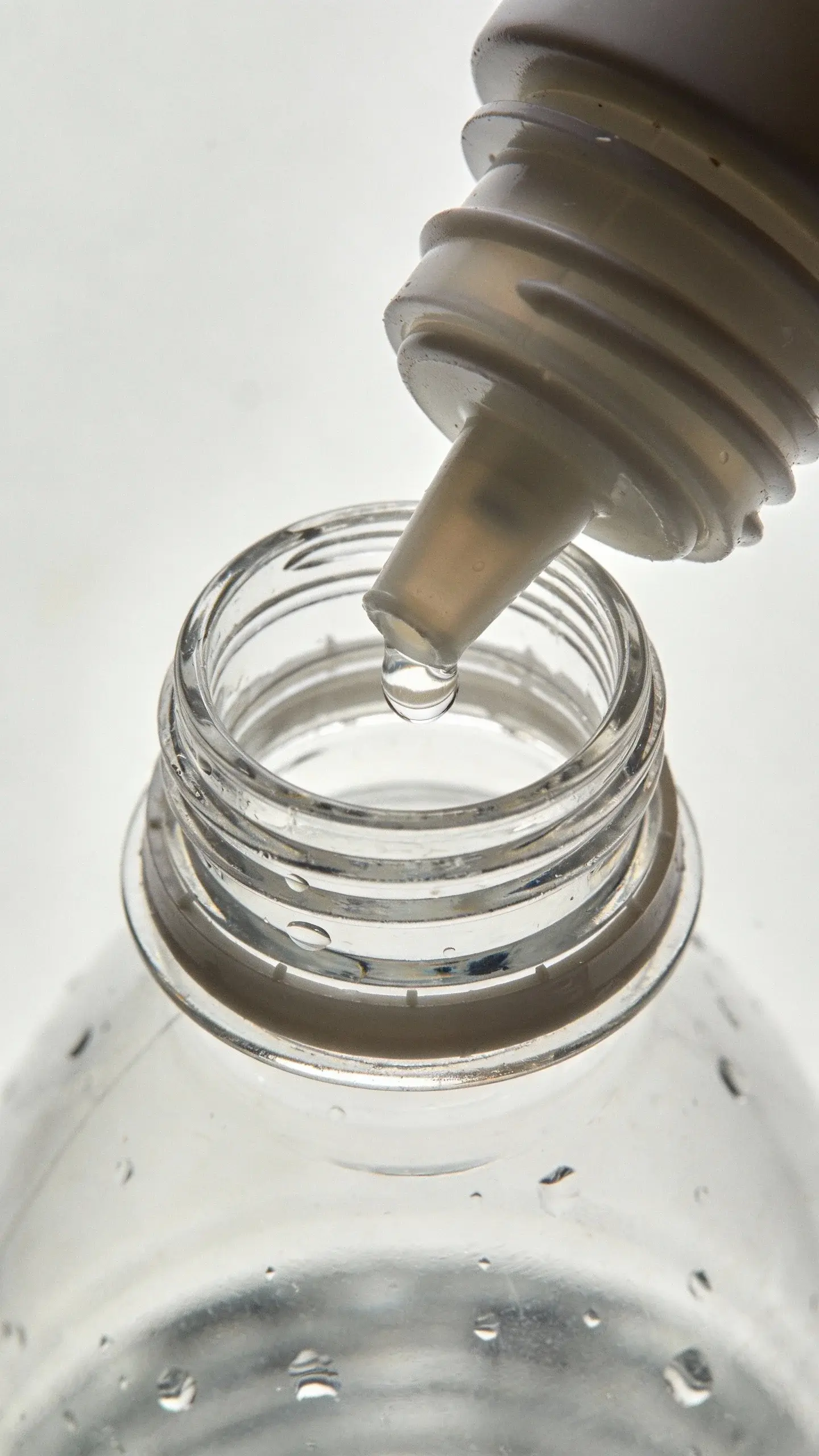 top view closeup of a water bottle nozzle with visible water droplet