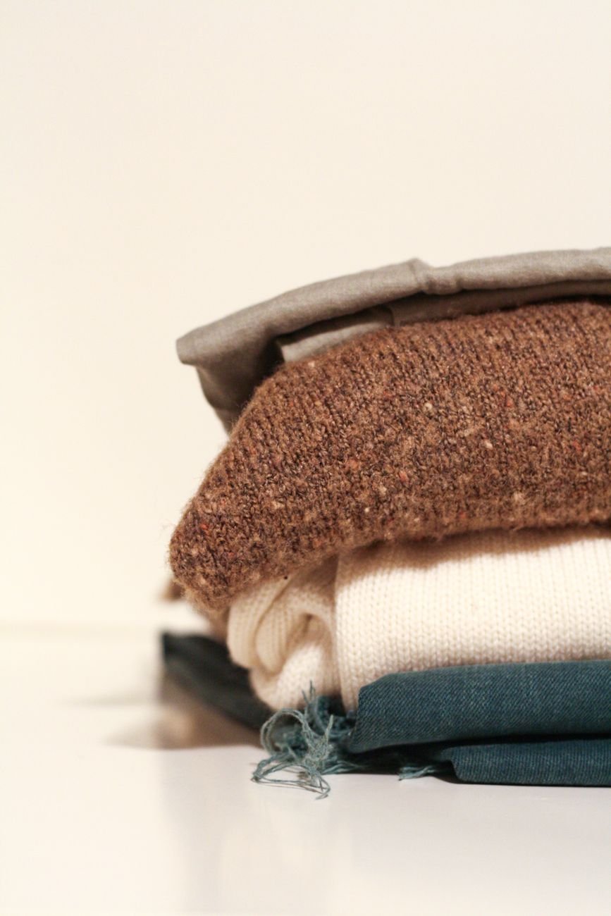 Folded clothes stacked neatly on a bed