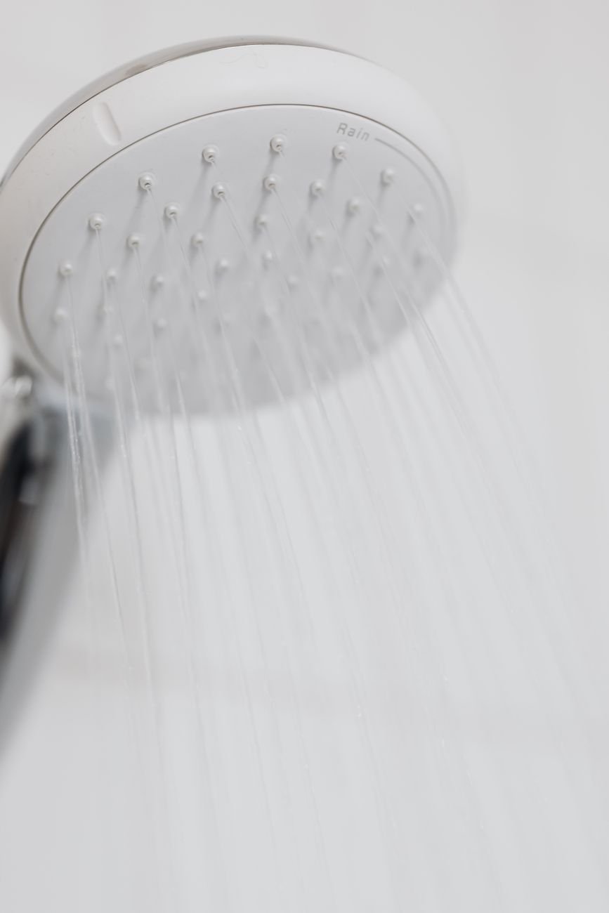 A chrome shower head with water running