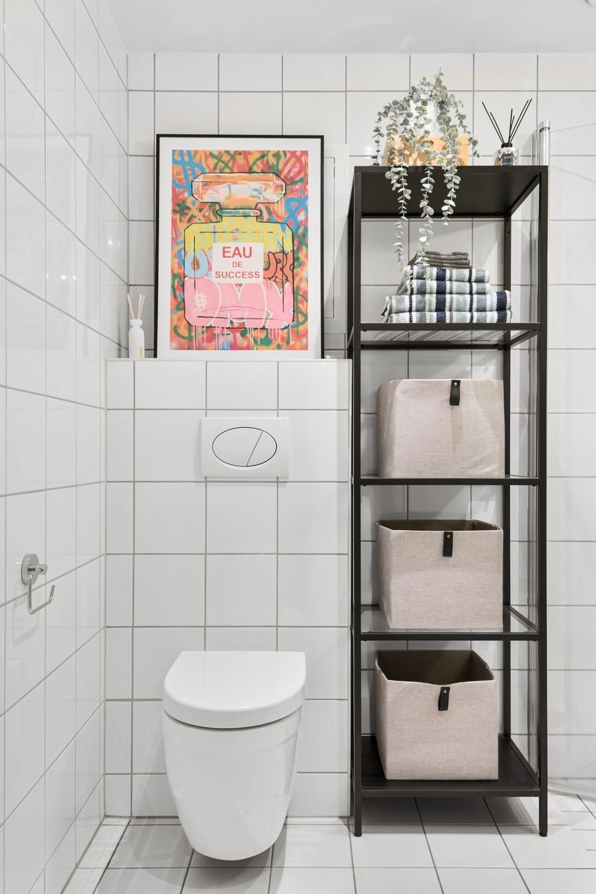 Shelves above a toilet holding towels and baskets