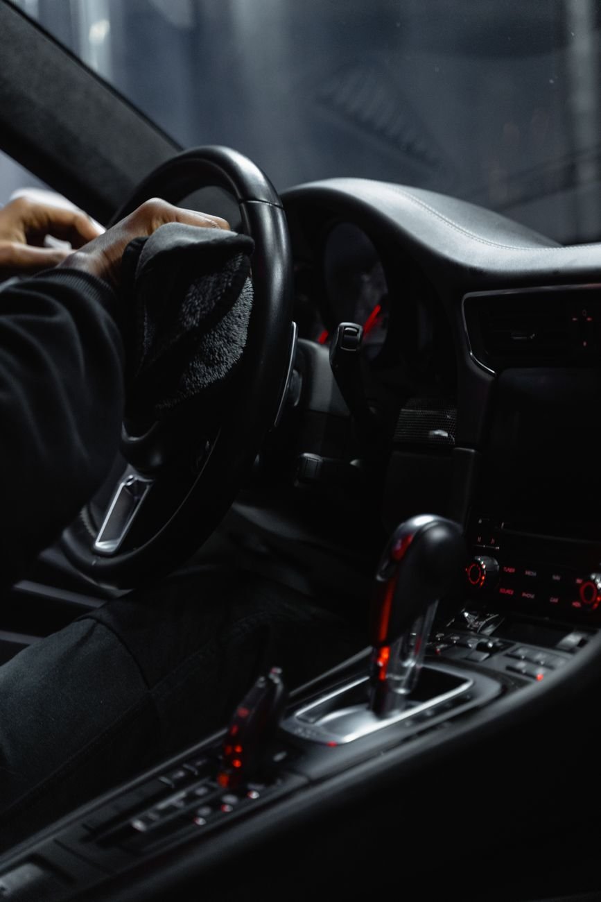 A person wiping a car dashboard with a microfiber cloth