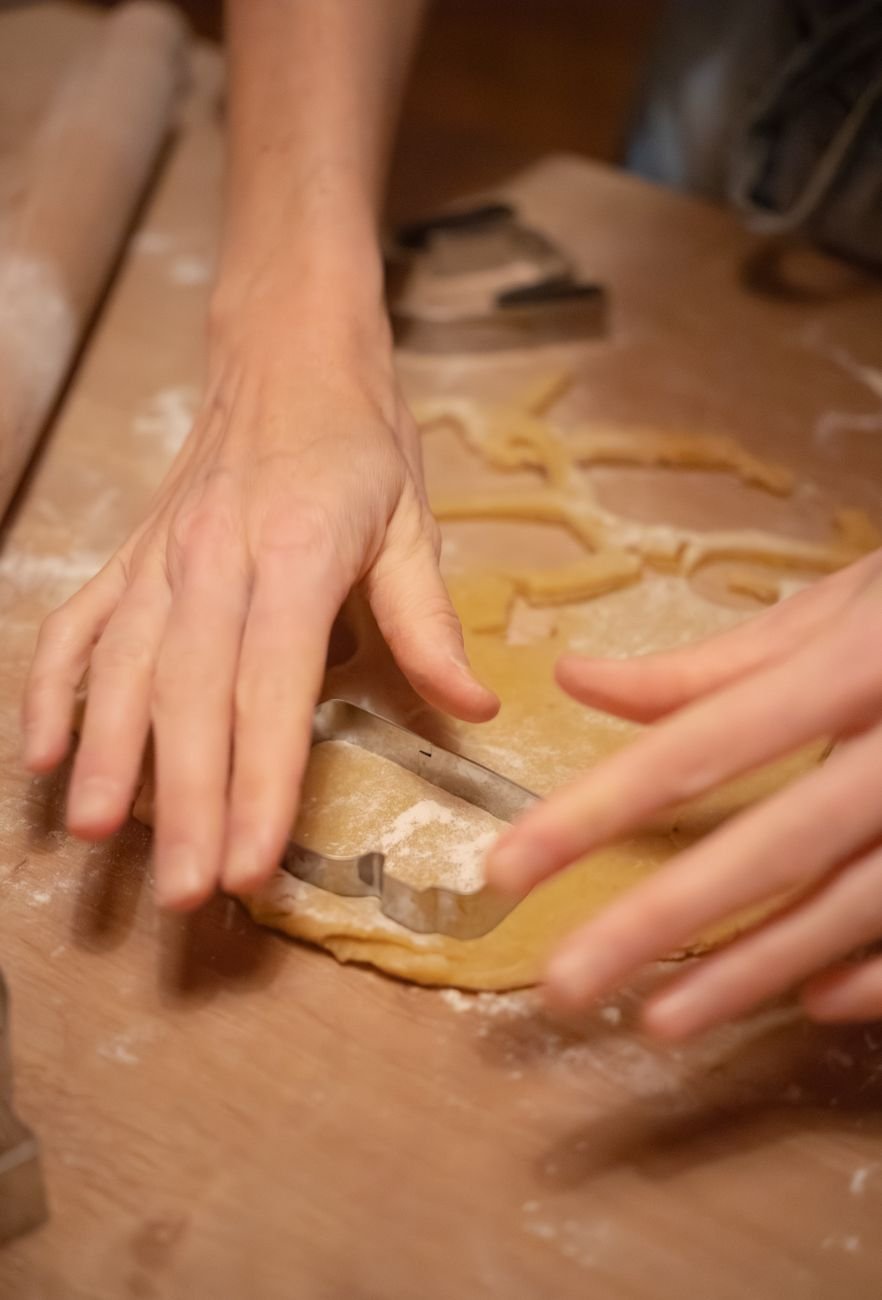 Hands cutting shapes out of rolled dough