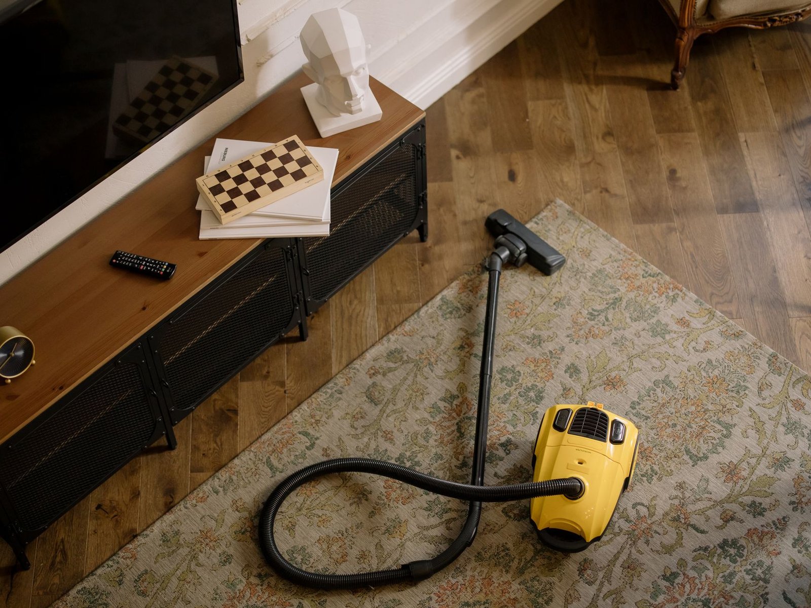 A bright tidy living room with a basket of cleaning supplies