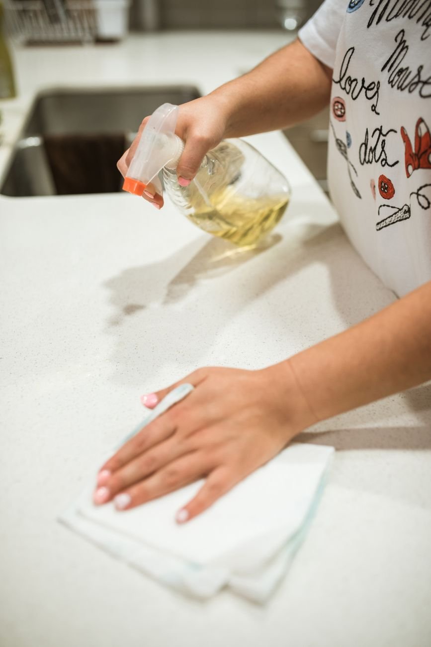 A person wiping a kitchen counter with a cloth