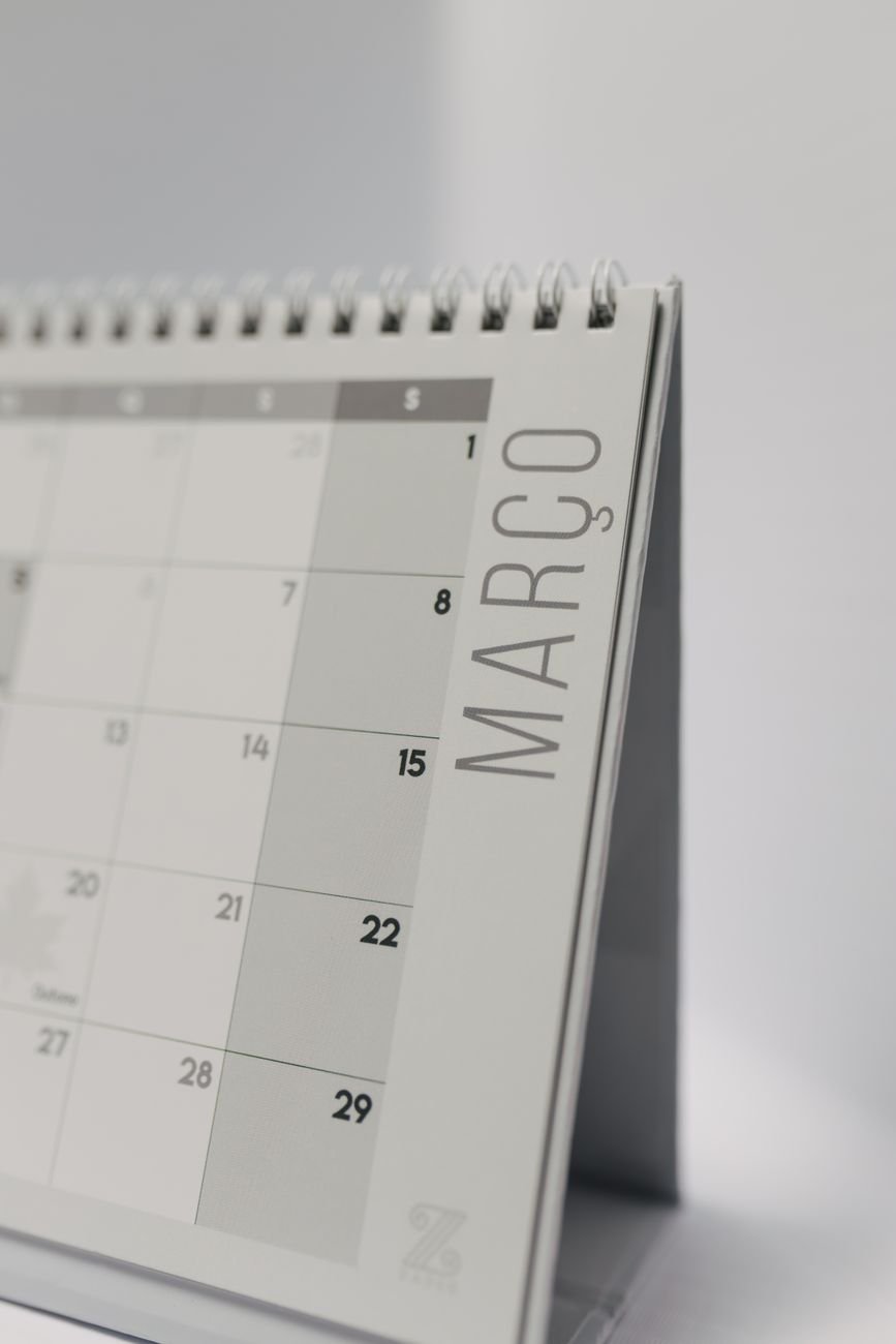 A wall calendar and planner on a desk