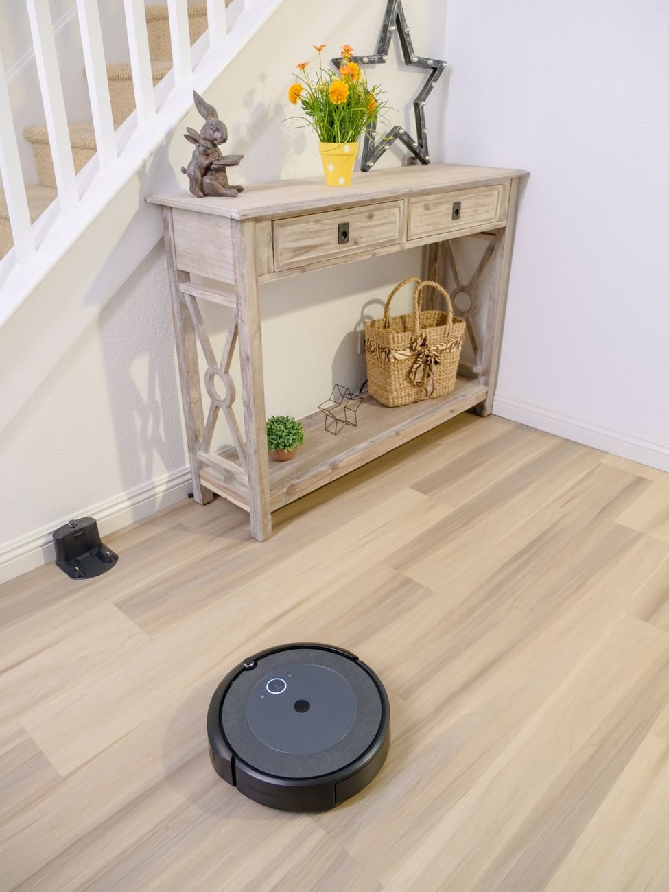 A robot vacuum cleaning a floor while a dog watches