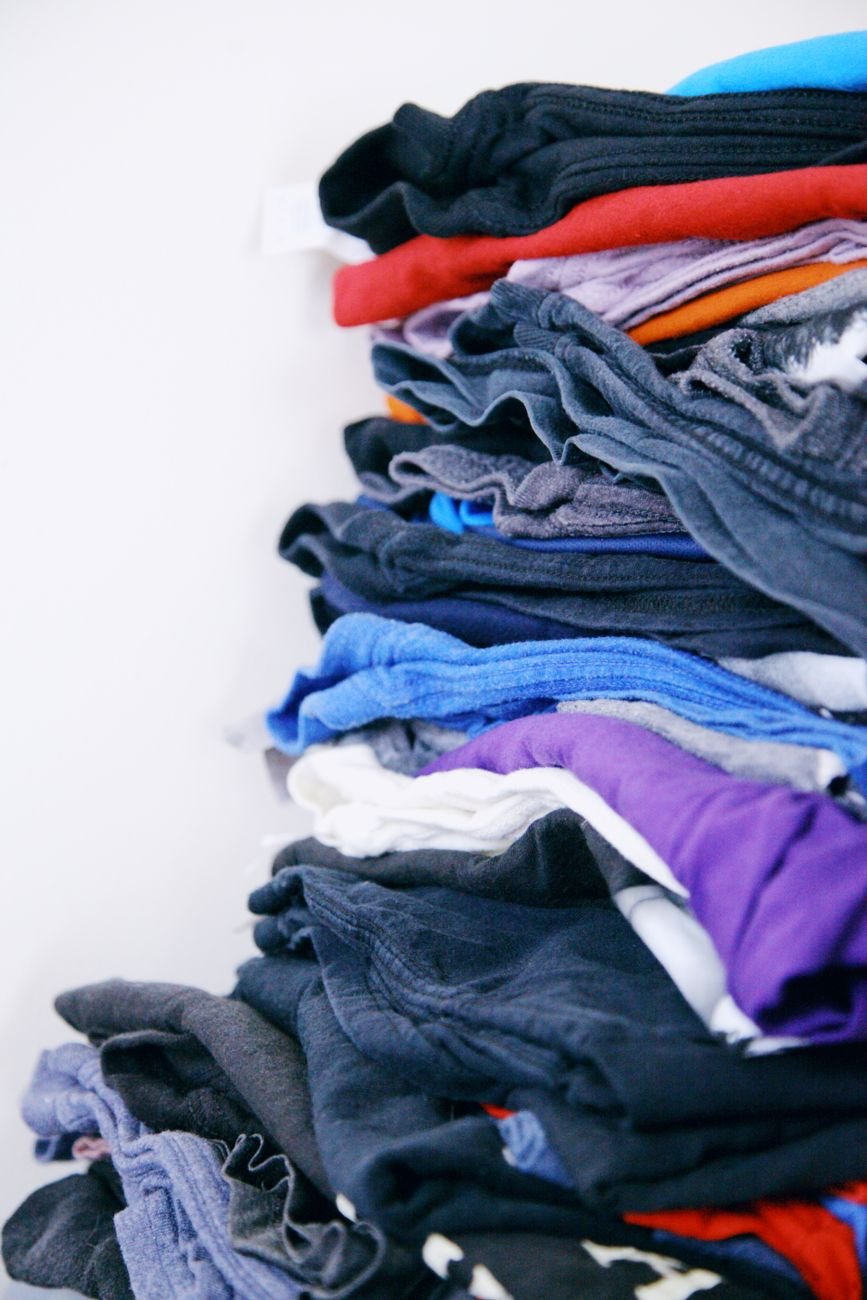 A pile of clothes being sorted into keep and donate stacks