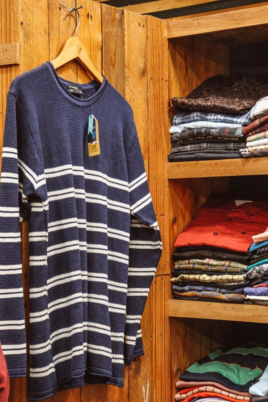 Folded sweaters stacked neatly on a closet shelf