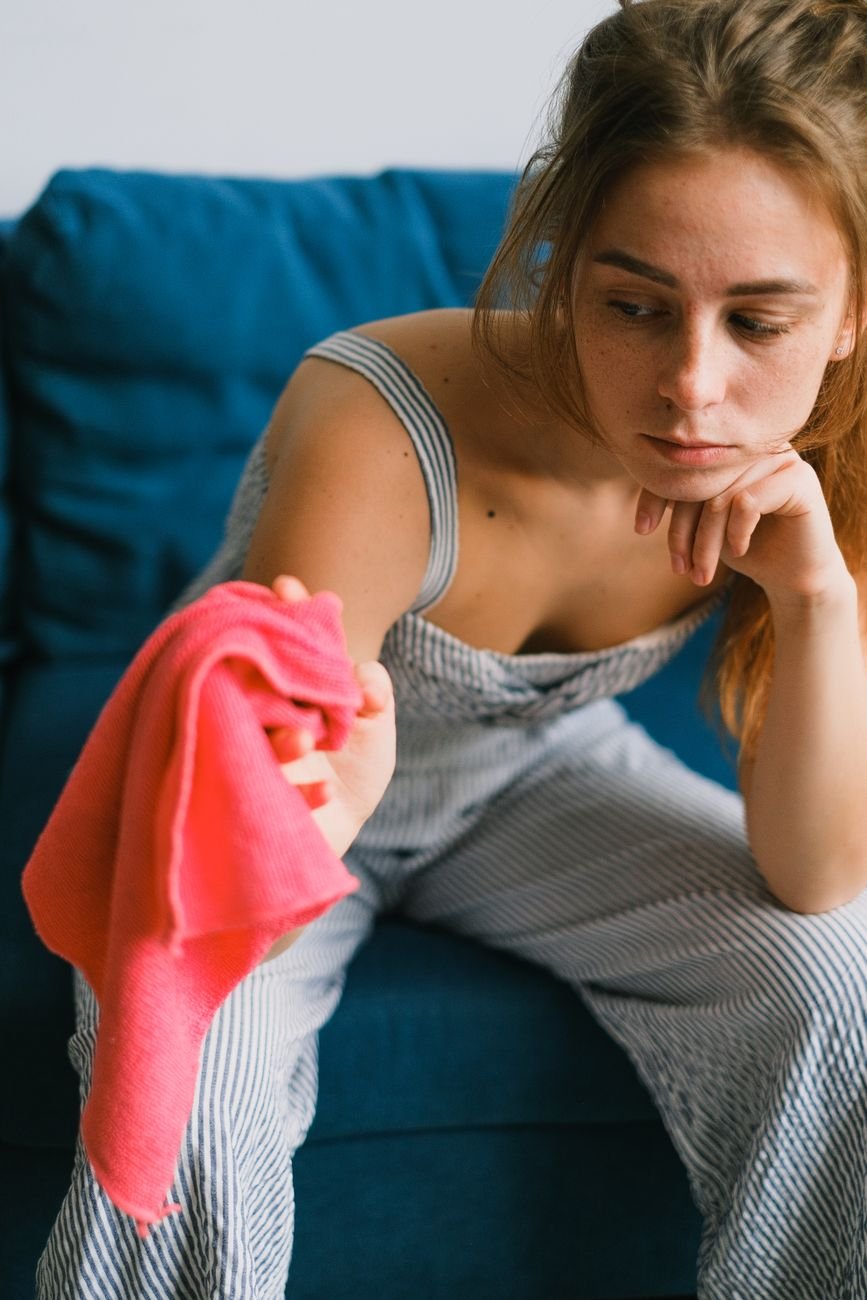 A hand scrubbing a stain on upholstery with a cloth