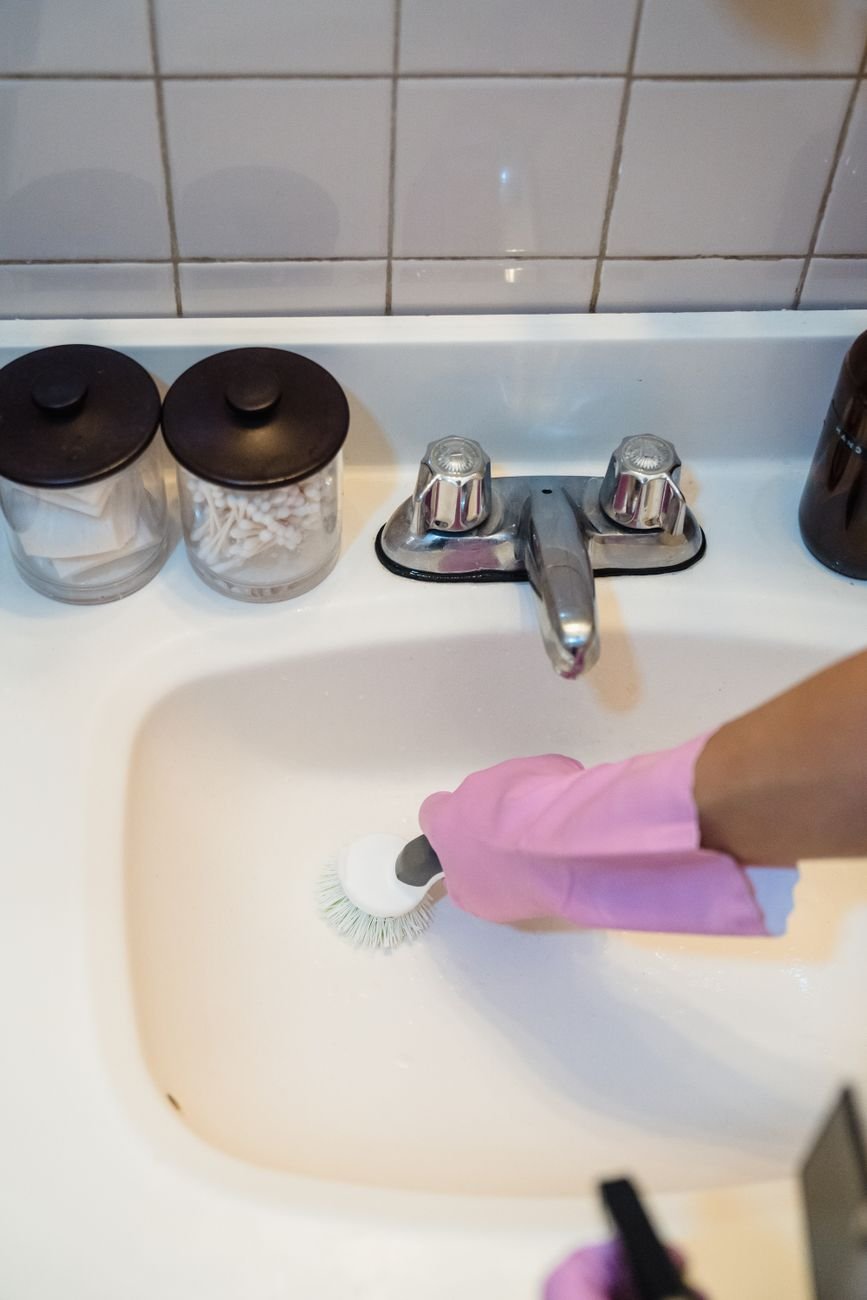 A person scrubbing a bathroom sink