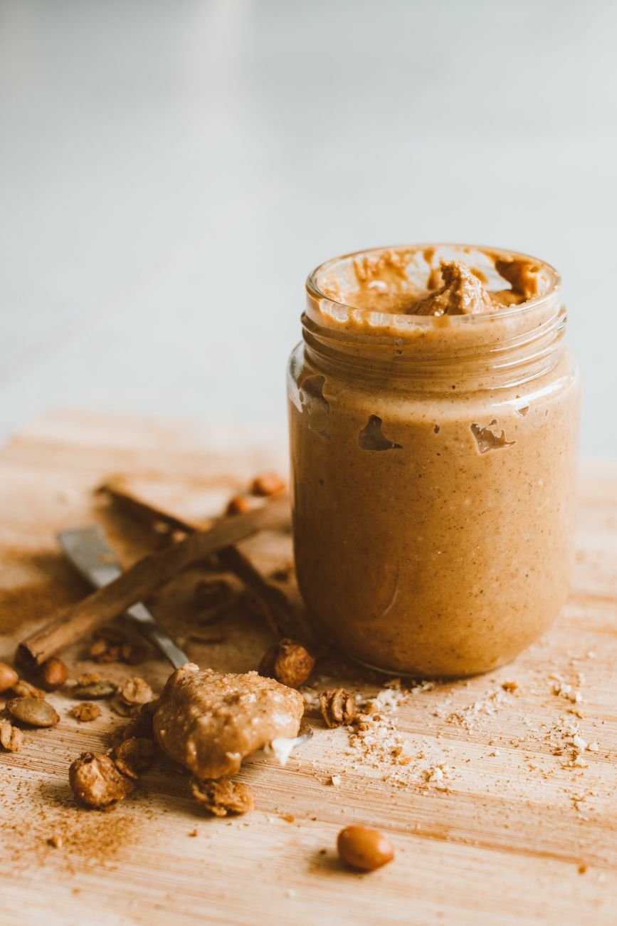 A jar of peanut butter and a spoon on a kitchen counter