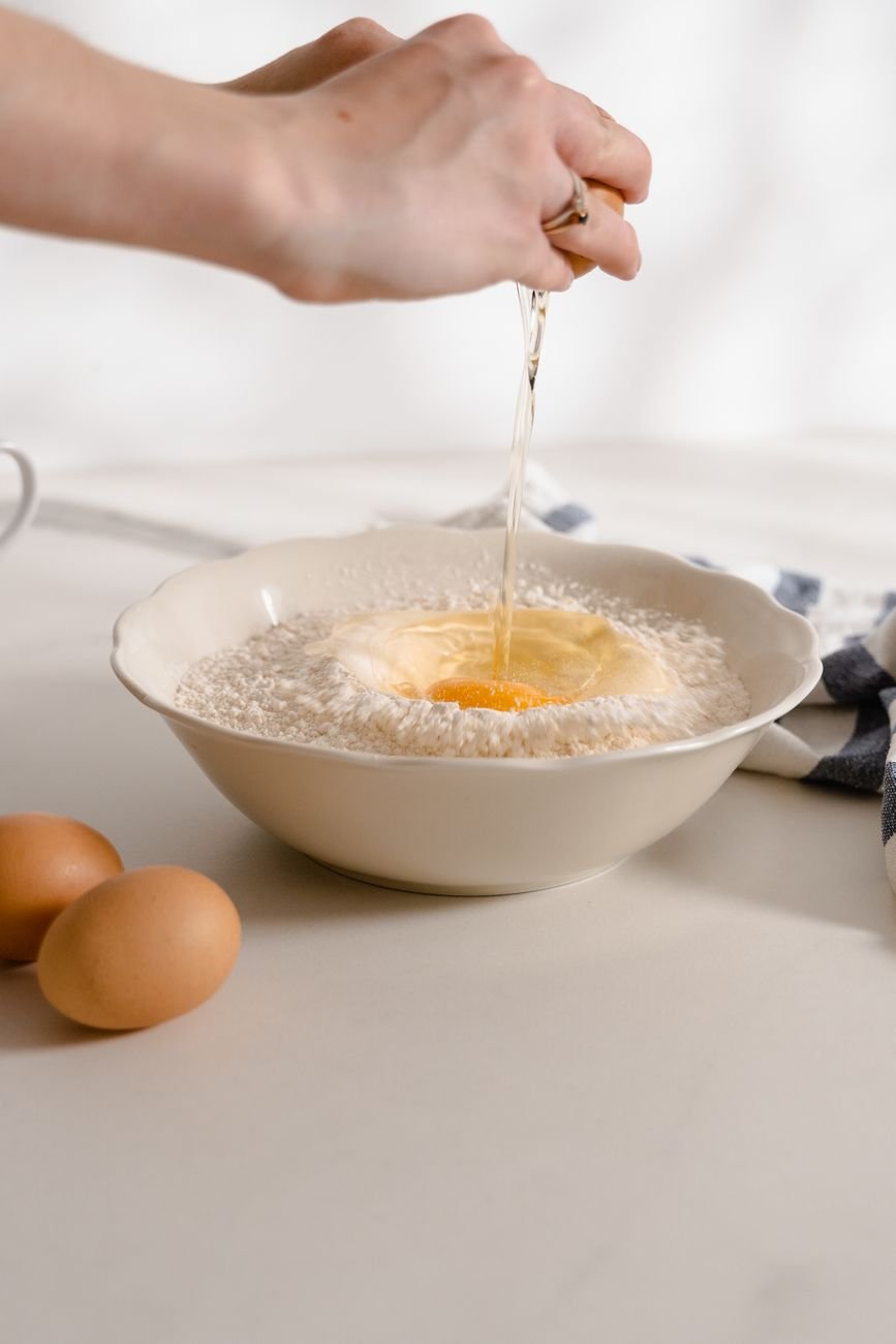 Cracking an egg into a bowl of flour for the cake batter