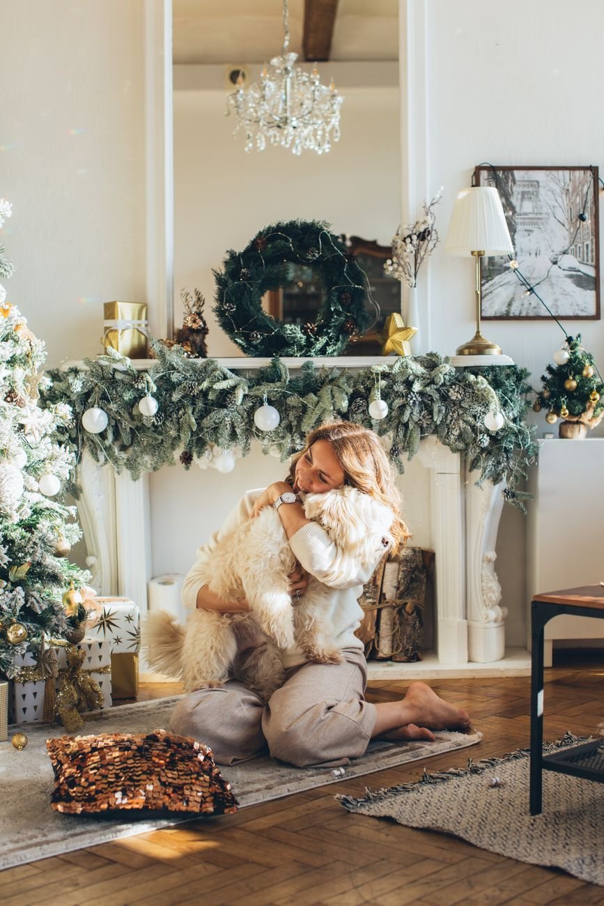 A person hugging their dog by the Christmas tree