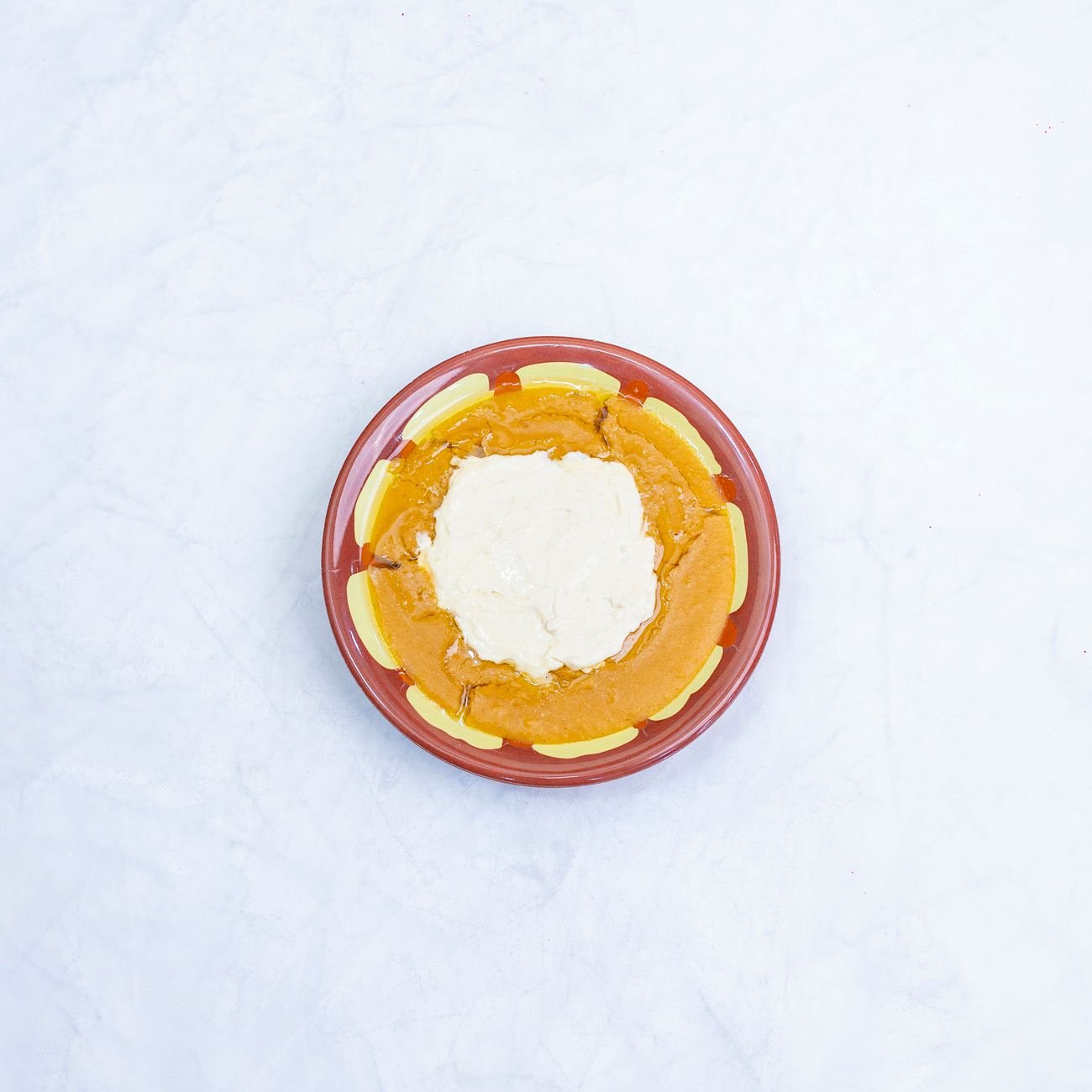 A bowl of pumpkin puree next to a whole pumpkin