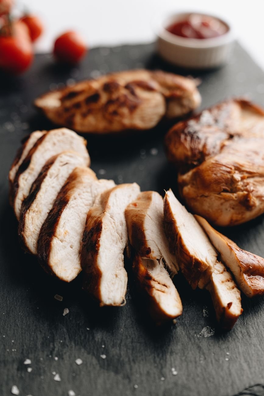 Cooked chicken breast sliced into thin strips on a board
