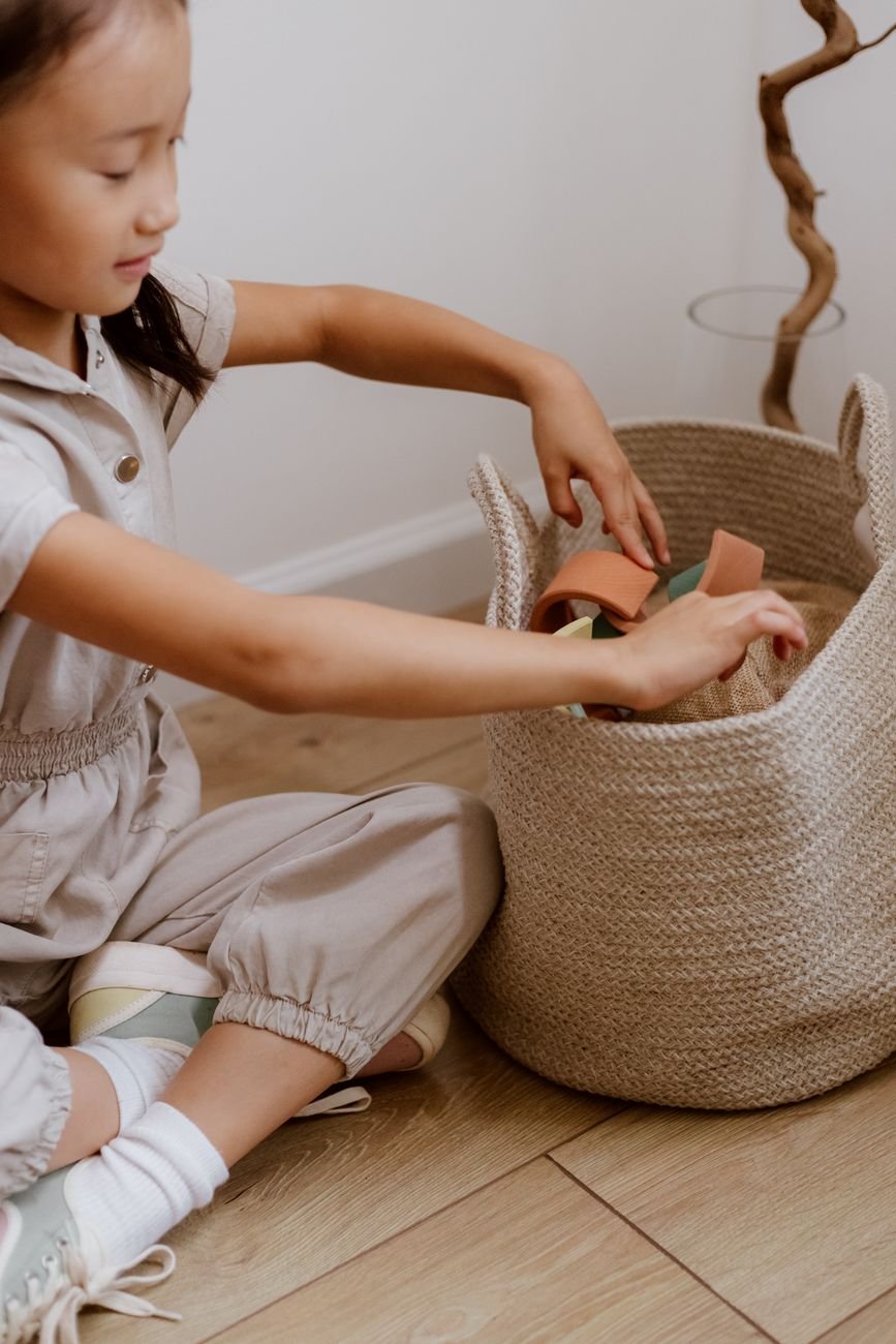 A child putting toys into a storage bin