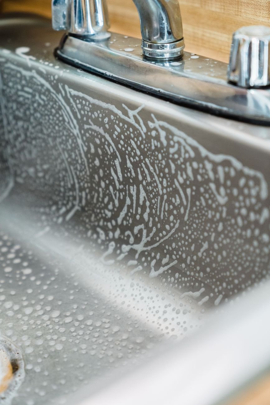 A sink filled with warm soapy water while someone cooks