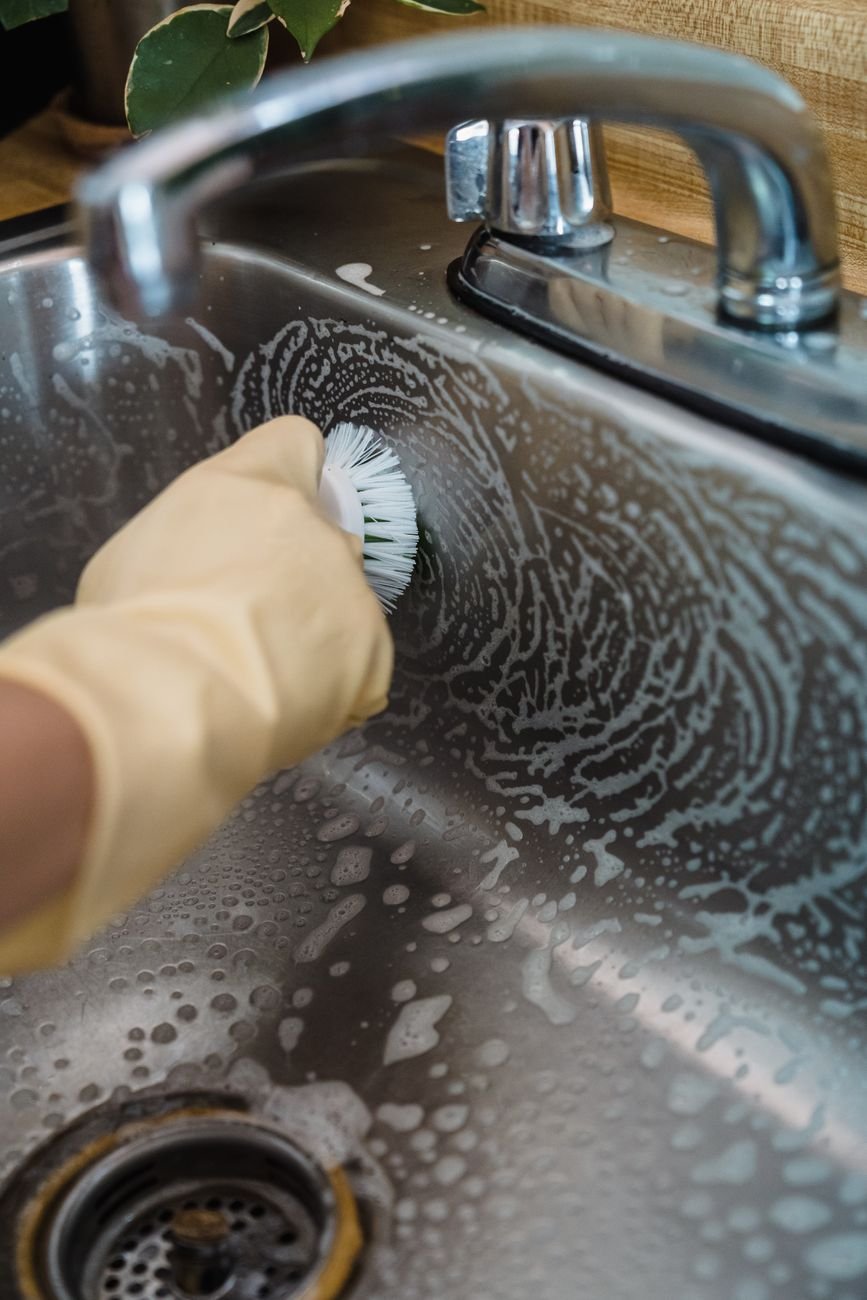 Scrubbing a stainless steel sink with a brush