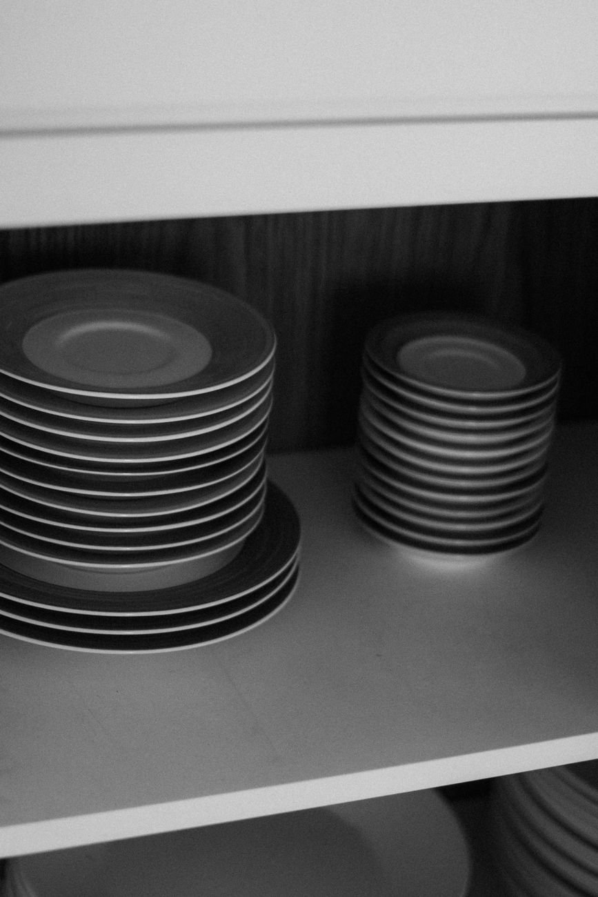 Plates and glasses neatly stacked inside an open kitchen cabinet