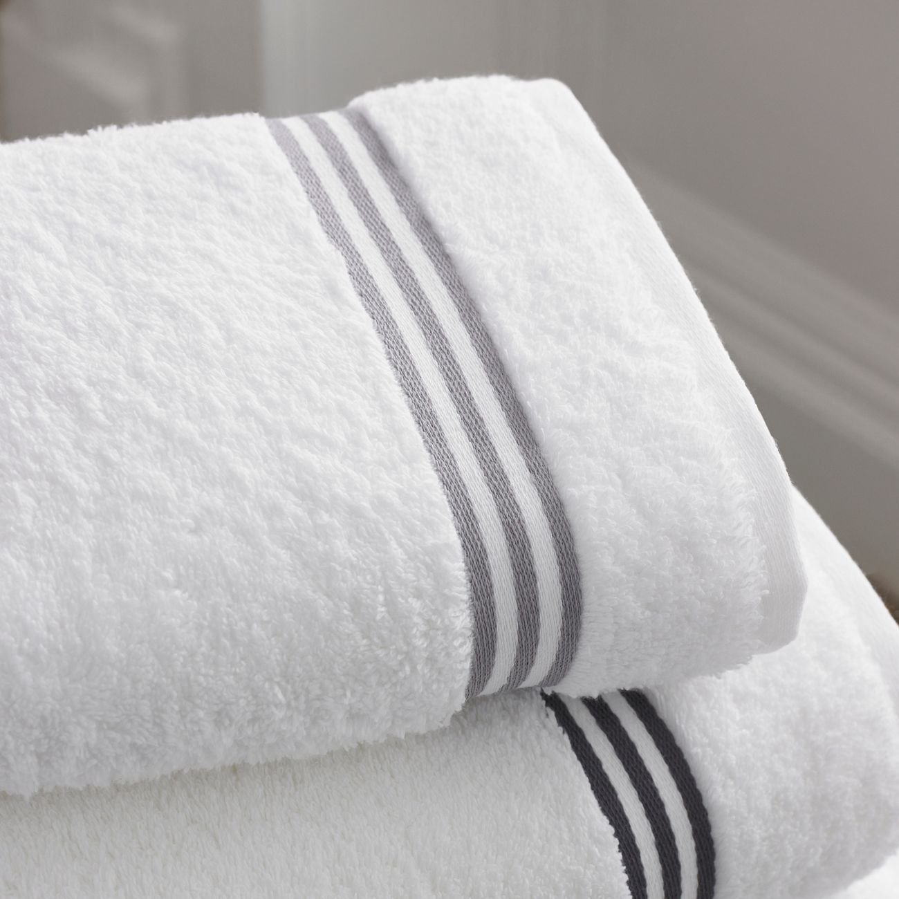 Hands folding a white towel on a bed