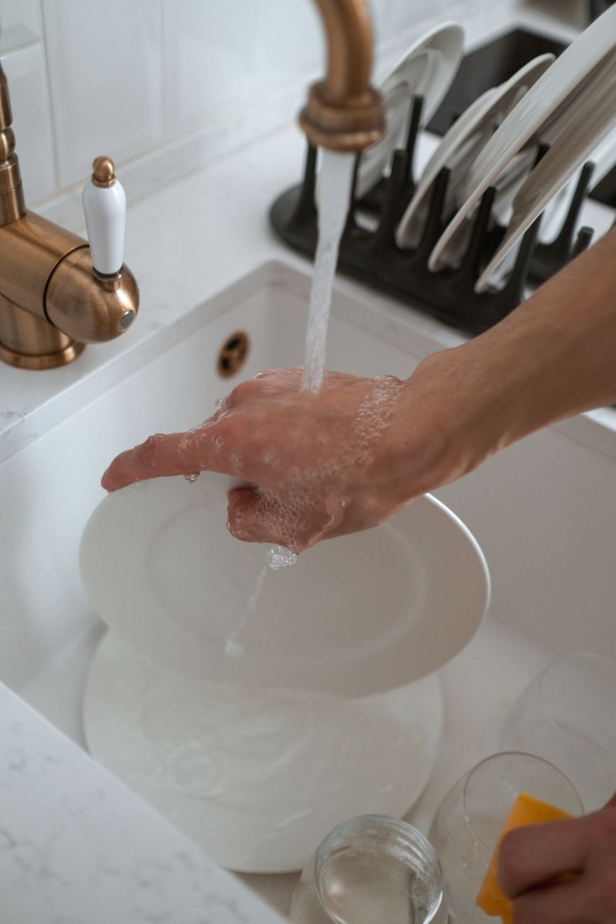 Washing a glass dish in soapy water at the sink