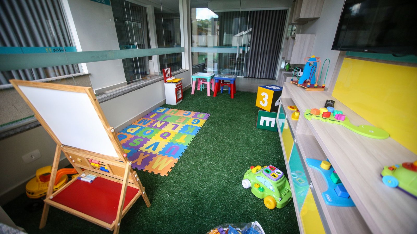 A bright, tidy playroom with low shelves, toy bins and a soft rug