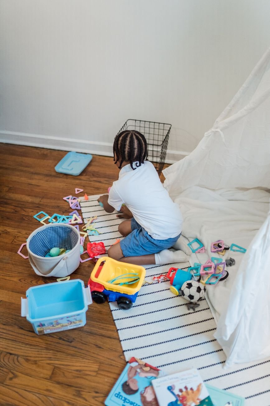 Toys spread across a playroom floor before a clean-up
