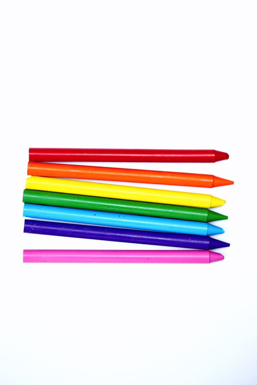 Crayons, paper and art supplies sorted in cups on a small table