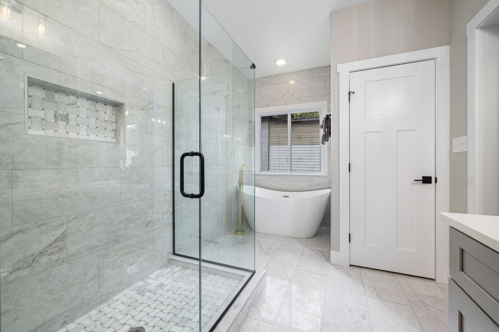 A clean walk-in shower with a clear glass door and bright white tile