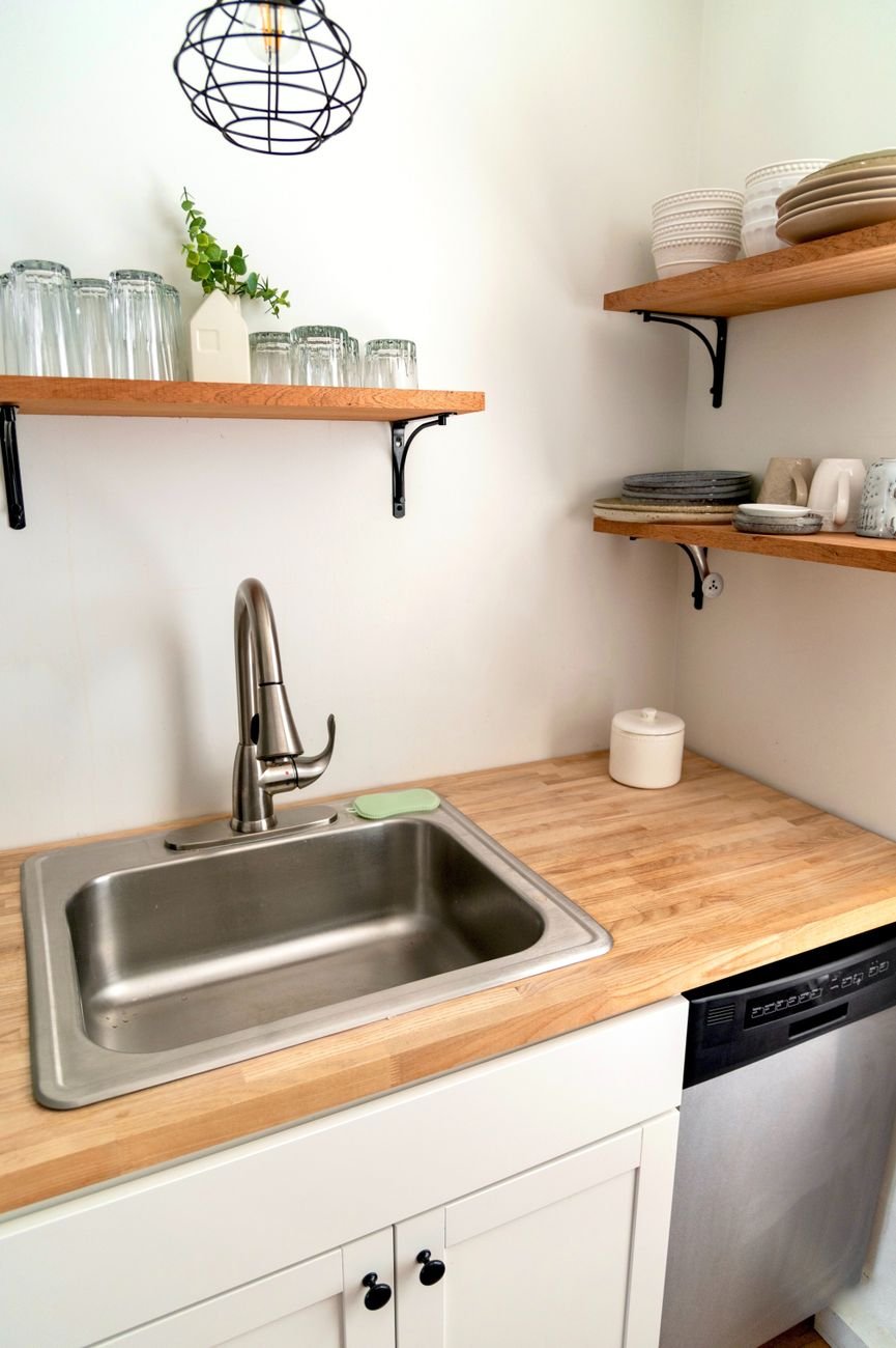A small kitchen with open shelving and hanging utensils