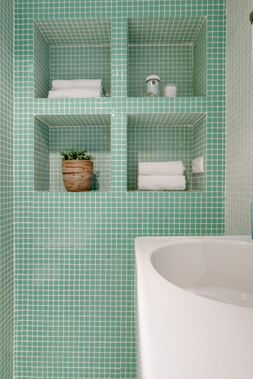 A small bathroom with shelves over the toilet