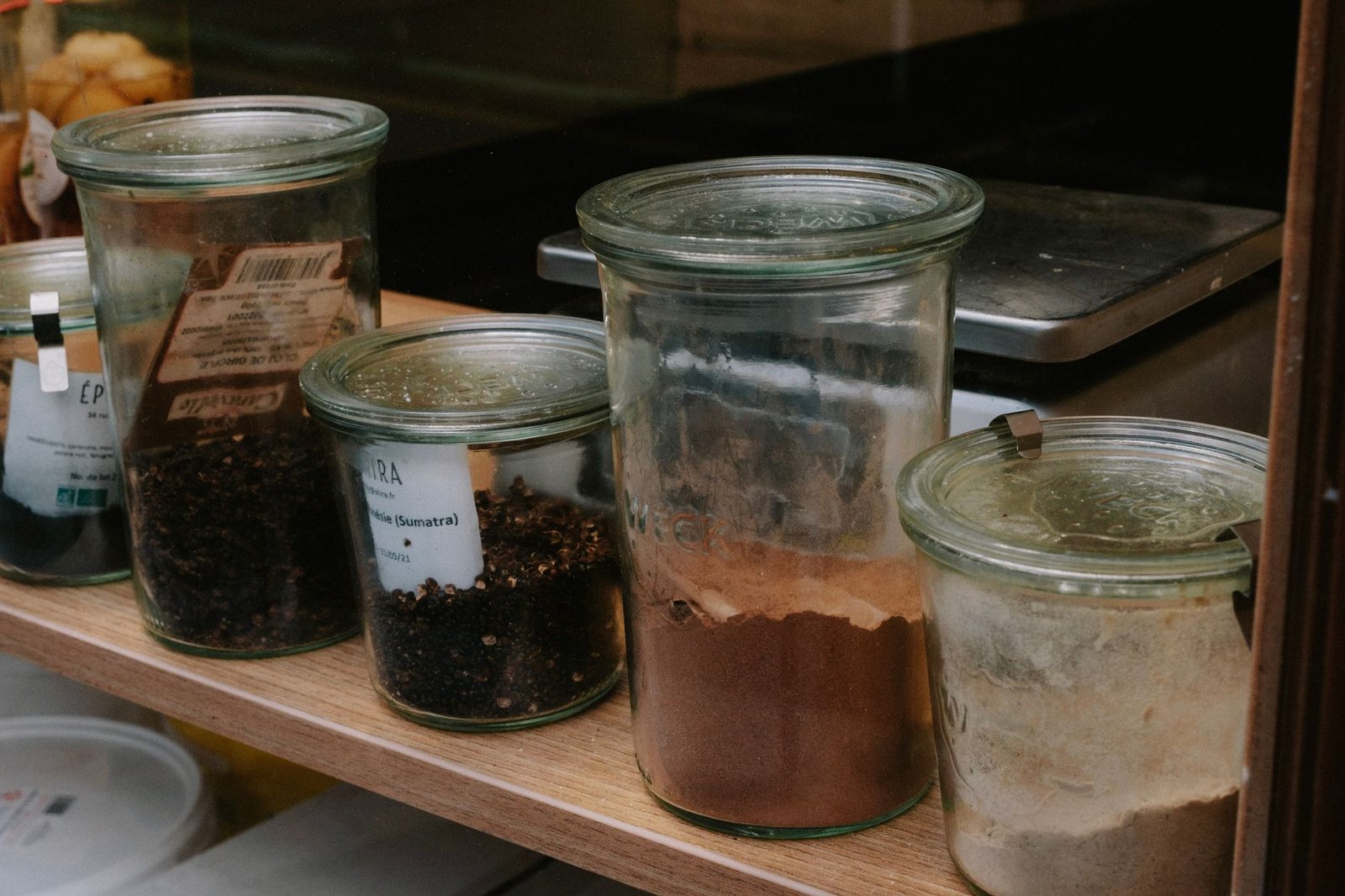 Neatly arranged glass spice jars on a kitchen shelf