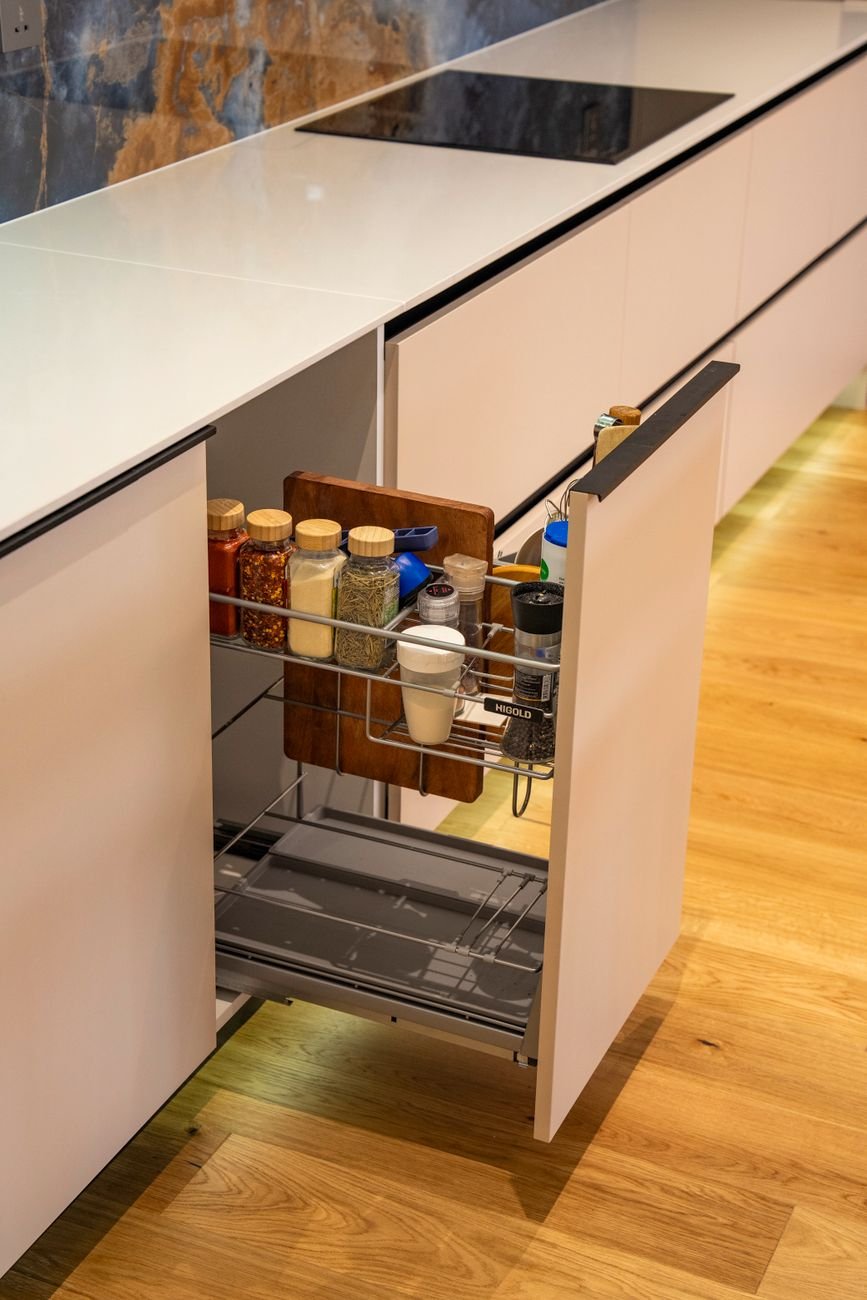 An open kitchen drawer filled with organized spice jars