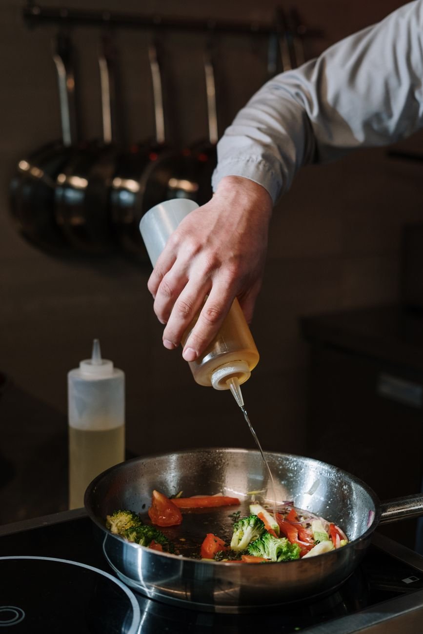 A person cooking and adding seasoning to a pan