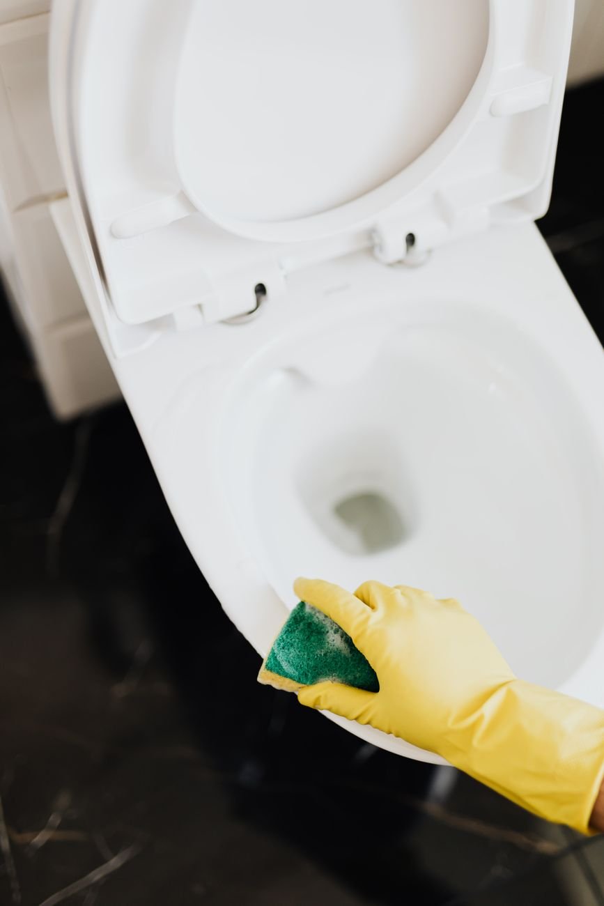 A person in rubber gloves scrubbing a toilet bowl