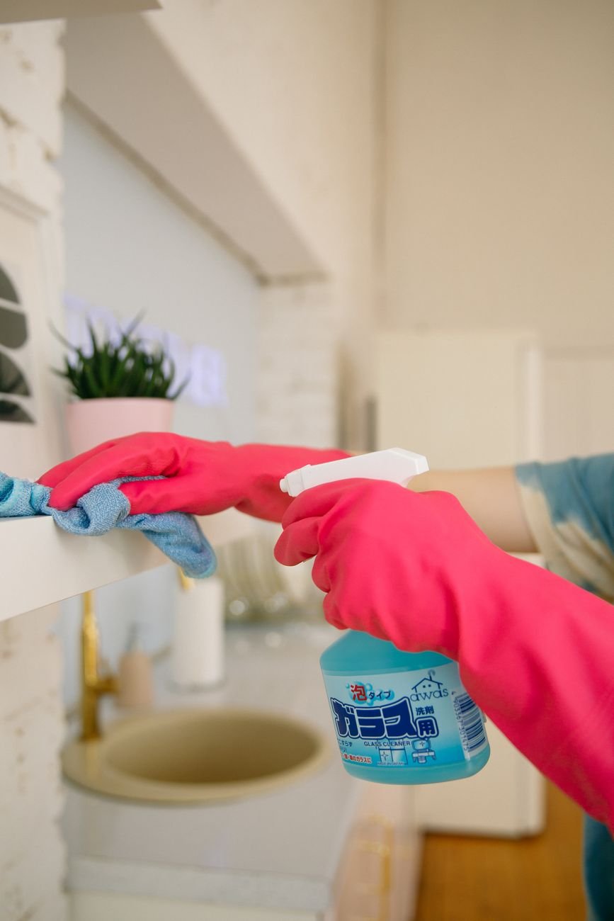 Cleaning spray bottles and sponges lined up on a counter