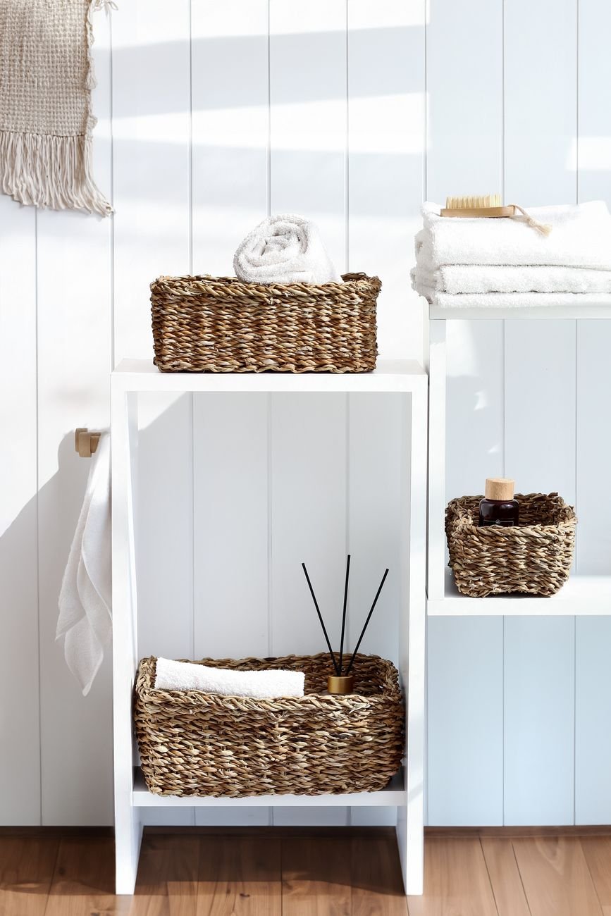 Rolled towels and toiletries in baskets in a bathroom