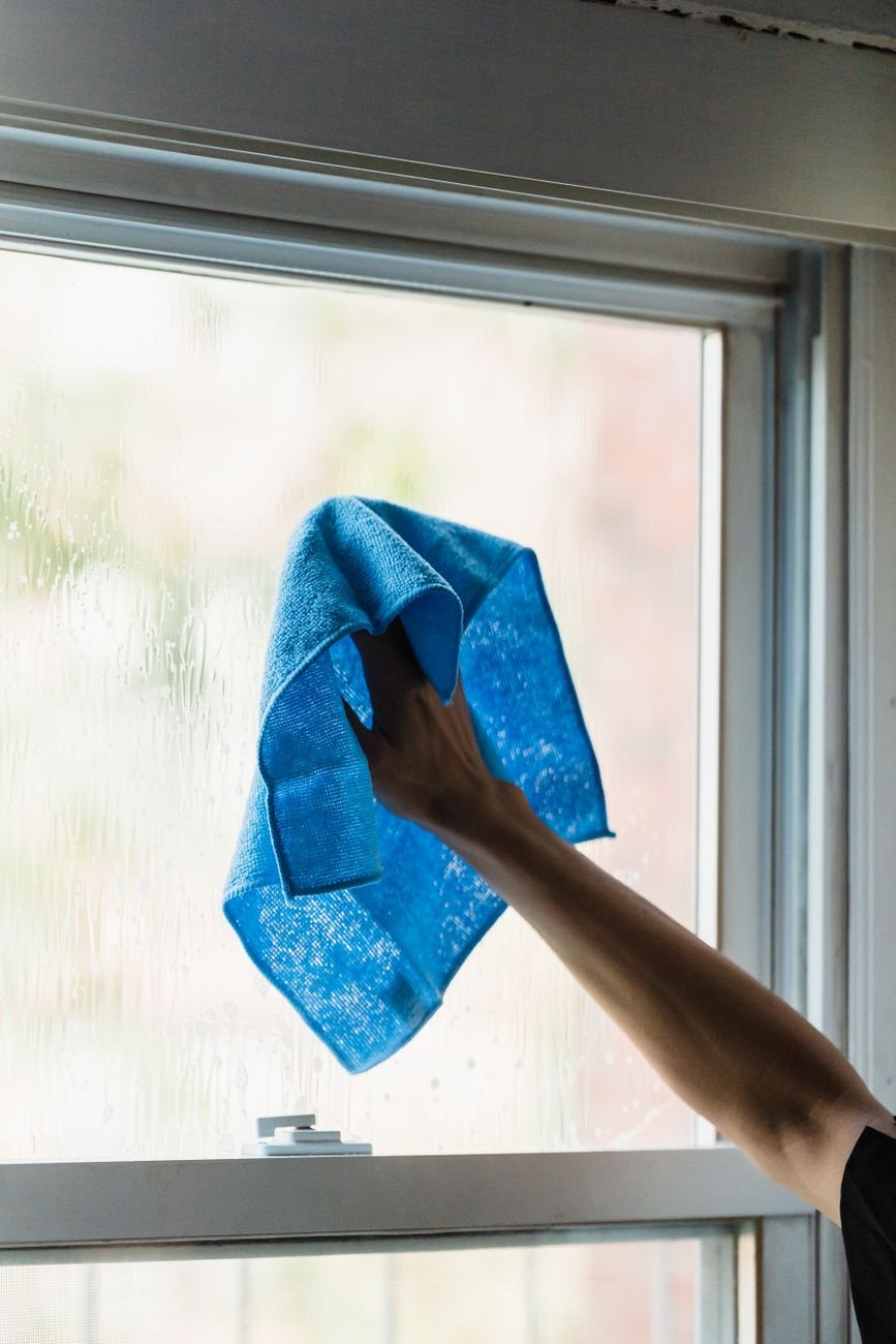 A hand wiping a window with a cloth